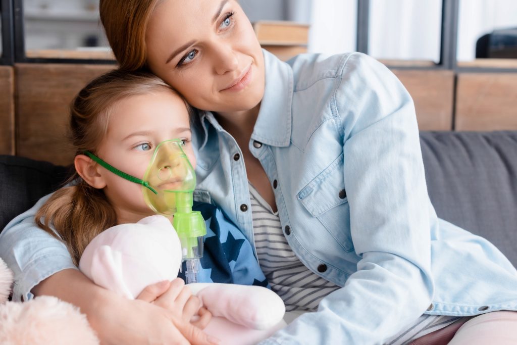 mother hugging asthmatic daughter in respiratory mask